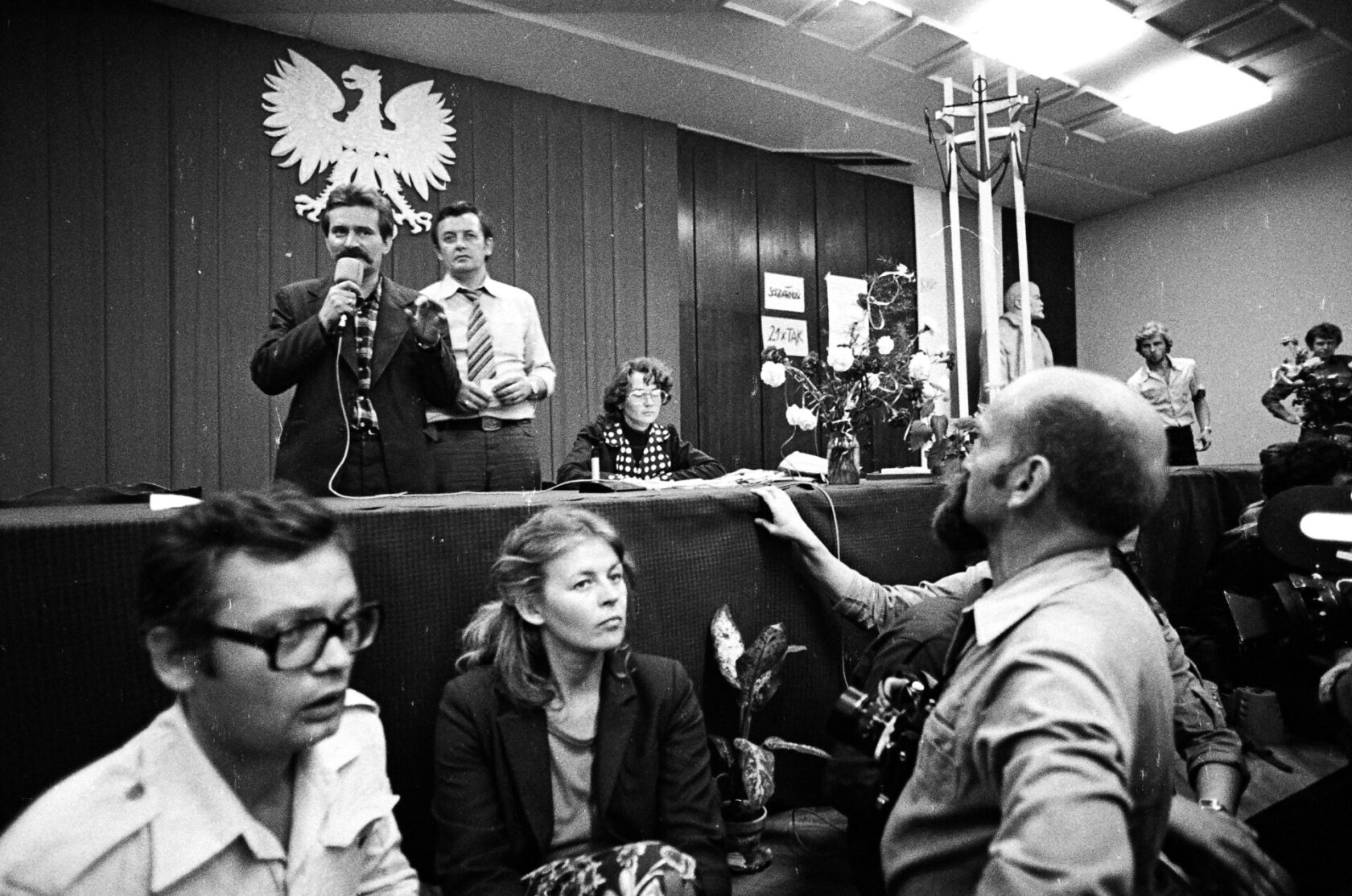 Przy stole konferencyjnym w Sali BHP podczas strajku sierpniowego siedzi Alina Pienkowska, obok stoją: Lech Wałęsa i Florian Wiśniewski, 29 sierpnia 1980